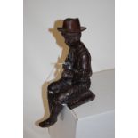 A mid-20th century bronzed figure of a seated child playing a pipe