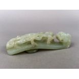 A Qing Dynasty Chinese pale celadon jade belt hook, carved and pierced with a dragon head terminal