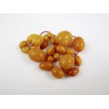 A necklace of ovoid butterscotch amber beads, 24 g, largest bead 24 mm x 20 mm, requiring re-