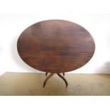 A George III oval tilt-top mahogany breakfast table, on short baluster columnar support with four