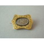 A Victorian yellow metal hairwork mourning locket, of cusped form, the face foliate engraved and