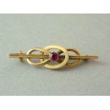 A 1920s garnet bar brooch, the millegrain set stone centrally mounted within an oval annulus, the