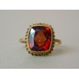 A mid 20th Century garnet cocktail ring, the faceted cushion cut stone of approximately 11mm,