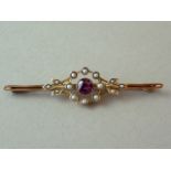 An almandine garnet and seed pearl bar brooch, the faceted stone centrally milligrain set and