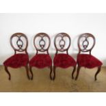 Four Victorian rosewood carved open-back dining chairs, each having overstuffed serpentine seat