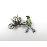 A novelty enamelled silver and marcasite brooch, modelled in the form of a gardener pushing a