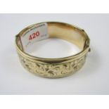 An early 20th Century 1/5 9ct rolled-gold hinged bangle, the face wrigglework and bright cut