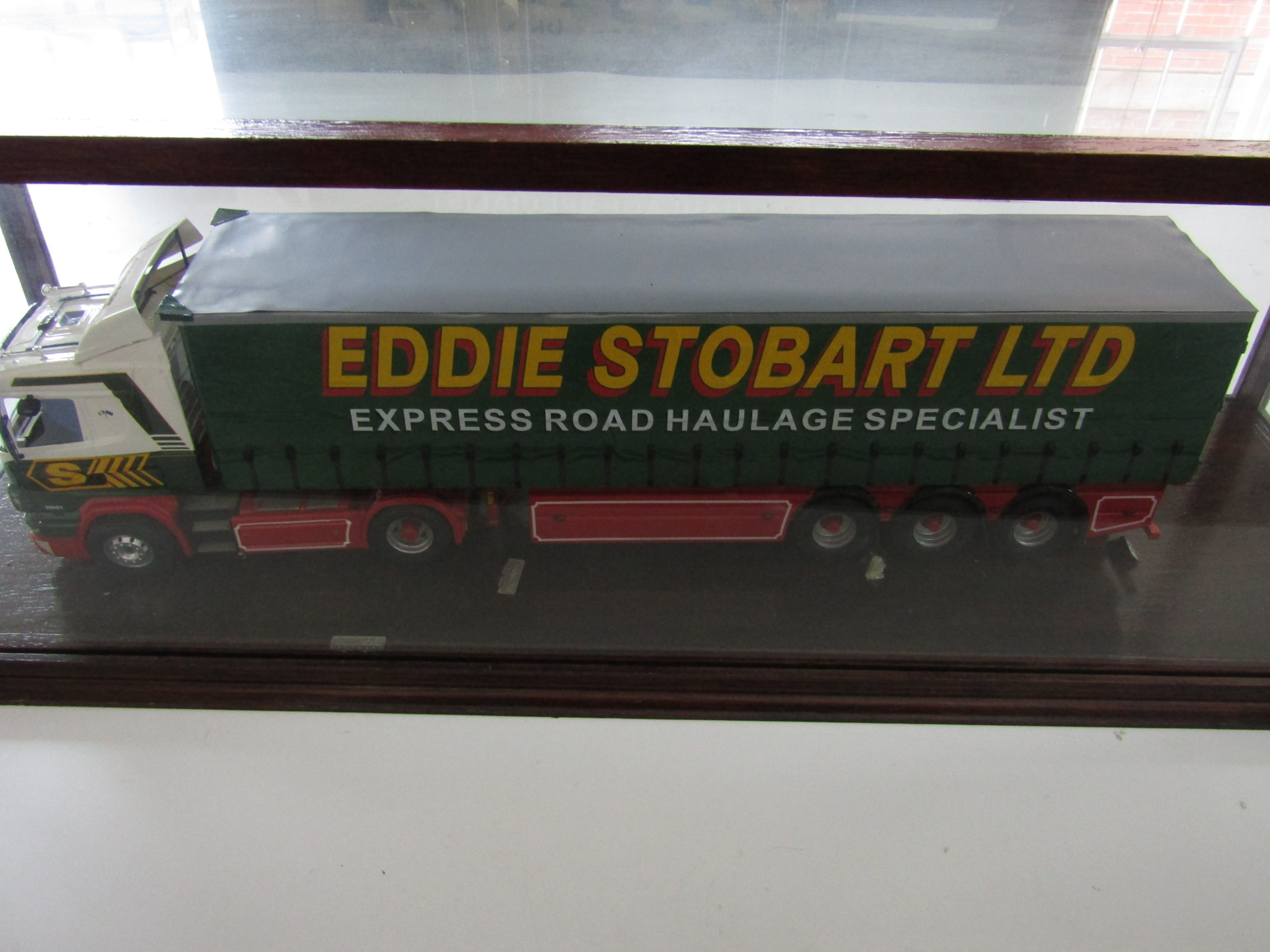 A large-scale hand-built model of an Eddie Stobart articulated lorry, in a glazed display case,