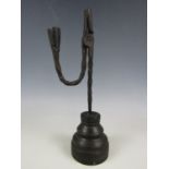 An antique wrought iron rush light, the nip and candle socket raised over a spirally twisted stem