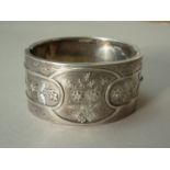 A Victorian silver hinged bangle, the face decorated with overlapping oval cartouches containing