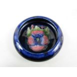 A William Moorcroft dish in the pansy pattern, impressed marks and blue signature, 11.5cm diameter