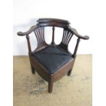 A George III mahogany corner commode armchair, the back having an idiosyncratic double crest, the