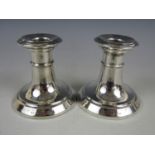 A pair of George V silver diminutive candlesticks, with spreading and stepped circular foot,