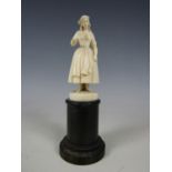 A finely carved ivory statuette of an 18th Century peasant girl, on a turned ebony socle, 19th