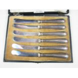 A George V cased set of six silver handled butter knives, with a moulded border incorporating a