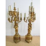 An impressive pair of gilt metal figural table lamps, modelled respectively as a boy and girl putto,