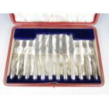 A cased set of six Edwardian silver handled fruit knives and forks, the handles of cladded and