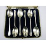 A cased set of six George V silver tea spoons, each having a crossed golf clubs device facing its