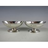 A pair of Victorian silver salts, each of navette form with gadrooned decoration, raised on an