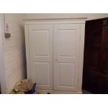 Painted pine wardrobe with a moulded cornice above two panelled doors on a plinth base raised on