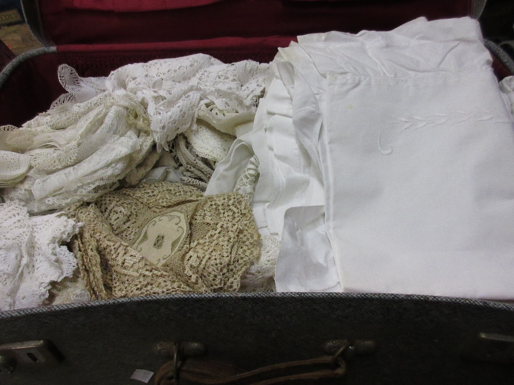 Grey suitcase containing a quantity of various linen and lace together with another grey suitcase