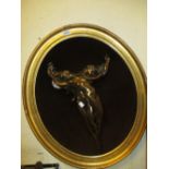 Modern bronzed composition wall plaque in the form of two naked figures in an oval gilt frame