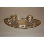 London silver inkstand having two clear cut glass bottles with hinged silver covers on low supports,