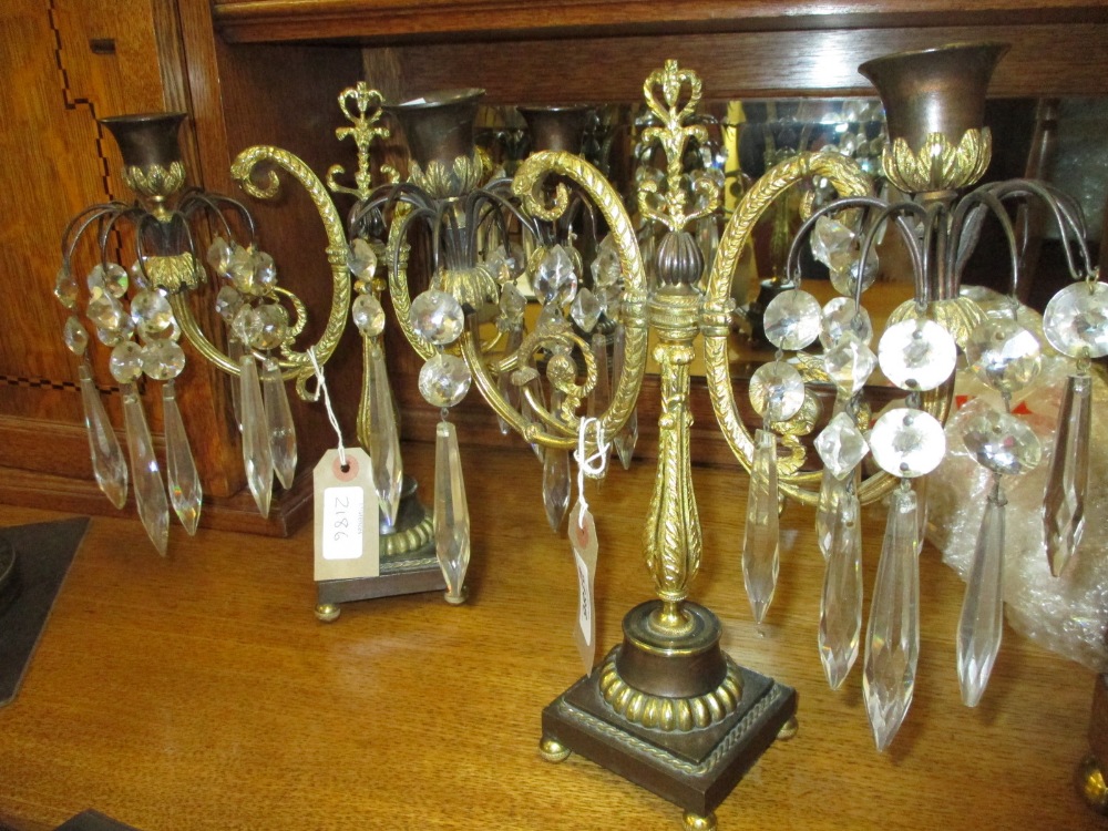 Pair of Regency gilded and brown patinated bronze two branch candelabra with glass drops