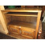 Reproduction oak dwarf bookcase with open shelves above two linen fold carved panel doors