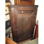 Early 20th Century oak standing corner cabinet with a single linen fold carved panel door