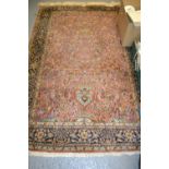 Qum rug with vase and all-over floral and bird design on a pink ground with borders,