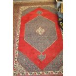 Bidjar style rug with centre medallion and multiple borders on a wine ground