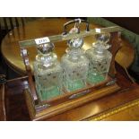 Early 20th Century oak and silver plate mounted three bottle tantalus (one bottle a/f)