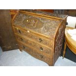 Arts and Crafts style carved oak bureau with a fall front above three drawers