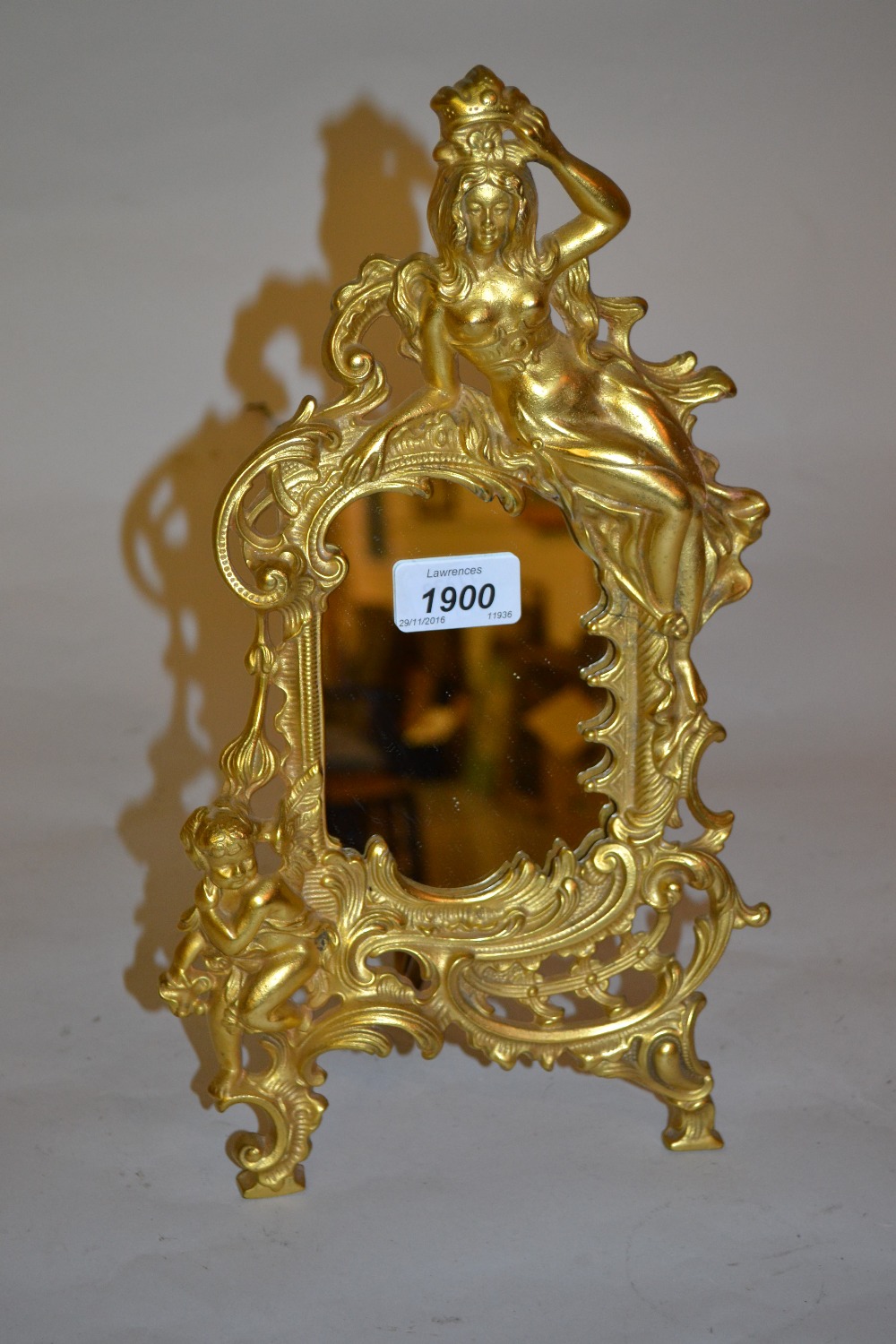 Gilt metal easel mirror surmounted by a figure of a lady