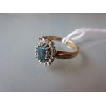 9ct Yellow gold ring with central blue topaz surrounded by a circle of diamonds and diamond chip