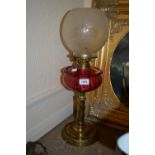 Victorian gilt brass oil lamp with a cranberry glass well and an etched glass shade