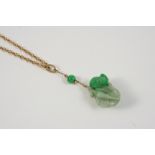 A CARVED JADE PENDANT depicting a mouse on a piece of fruit, 2.5cm. long, on a gold chain.