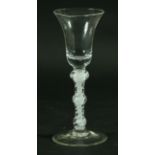 AN EIGHTEENTH CENTURY WINE GLASS, the bell shaped bowl above a triple knopped, white enamel stem