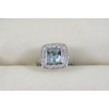 AN AQUAMARINE AND DIAMOND CLUSTER RING the square-cut aquamarine is set within a surround of