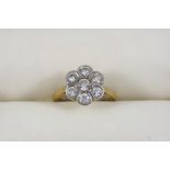 A DIAMOND CLUSTER RING of flower head form, set with seven circular old brilliant-cut diamonds, in