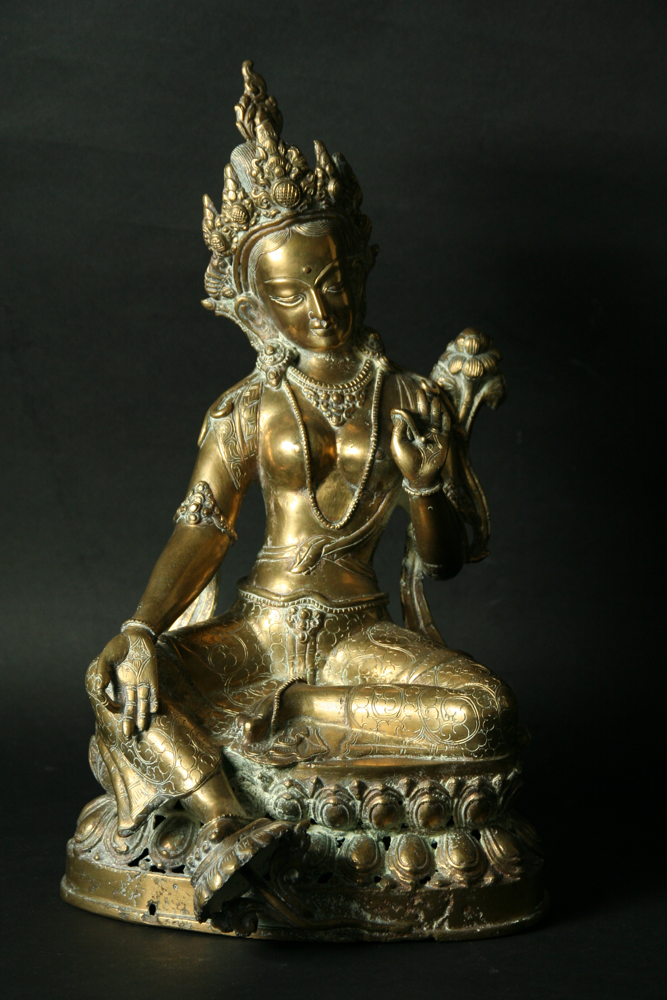 A BRONZE FIGURE of a seated female deity, 13ins. (33cms.) high