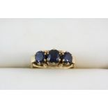 A SAPPHIRE THREE STONE RING set with three oval-shaped sapphires, in gold. Size Q.