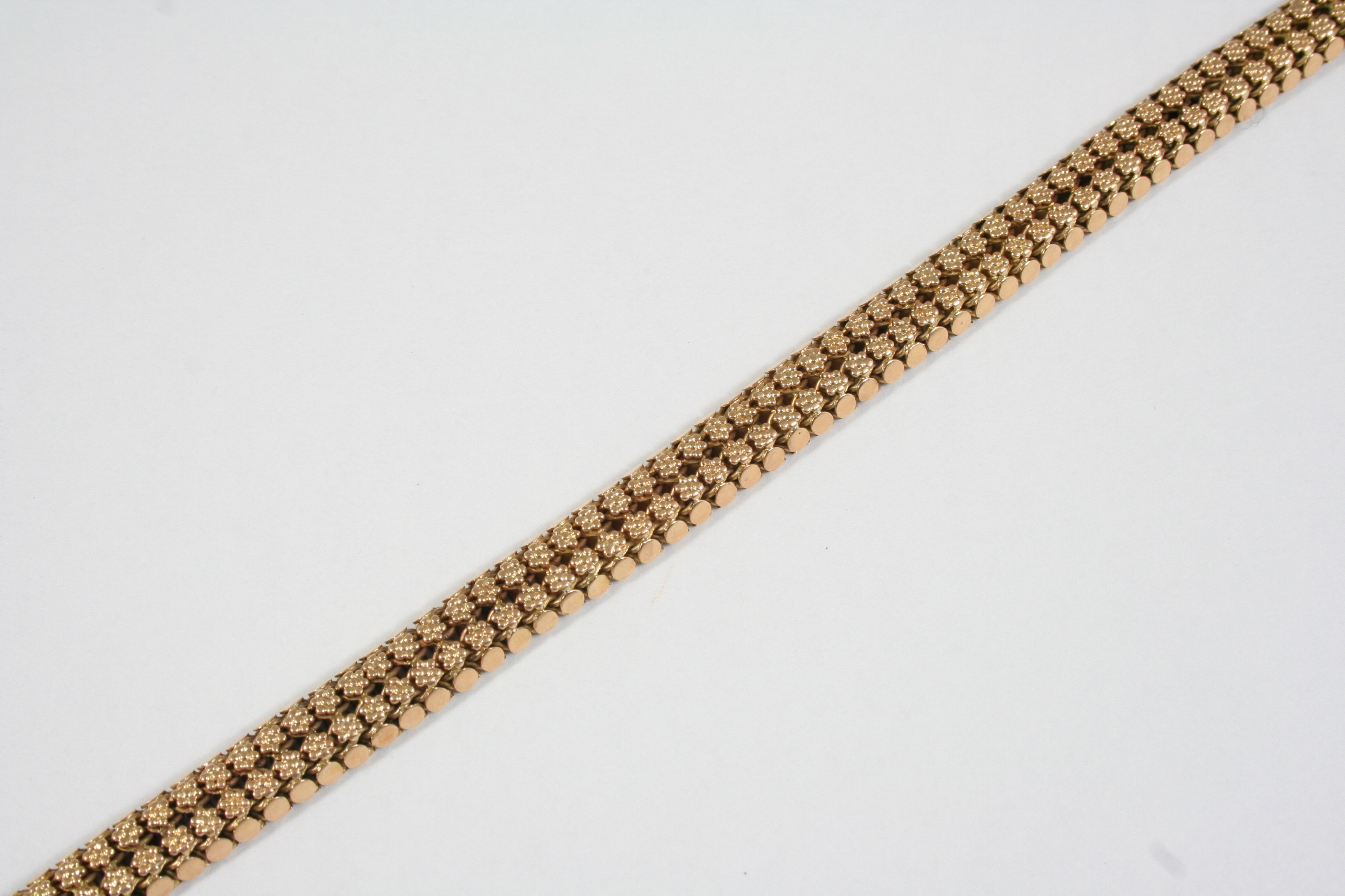 A GOLD FANCY LINK BRACELET formed as two rows of small flower heads, with concealed clasp, 19cm.