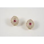 A PAIR OF RUBY AND DIAMOND FLOWER HEAD EARRINGS each centred with a circular-cut ruby within a