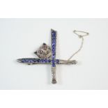 A SILVER AND GEM SET CROSS SWORDS BROOCH the tiger's head with ruby eyes, the swords set with