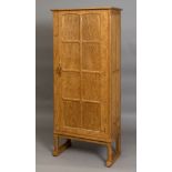 COTSWOLD SCHOOL GUN CABINET - OLIVER MOREL an oak gun cabinet with a fitted interior, with