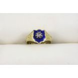 AN ENAMEL AND DIAMOND MEMORIAL RING the blue enamel shield is centred with a cushion-shaped diamond,