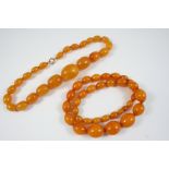 A SINGLE ROW GRADUATED AMBER BEAD NECKLACE 50cm. long, 57 grams, together with another graduated