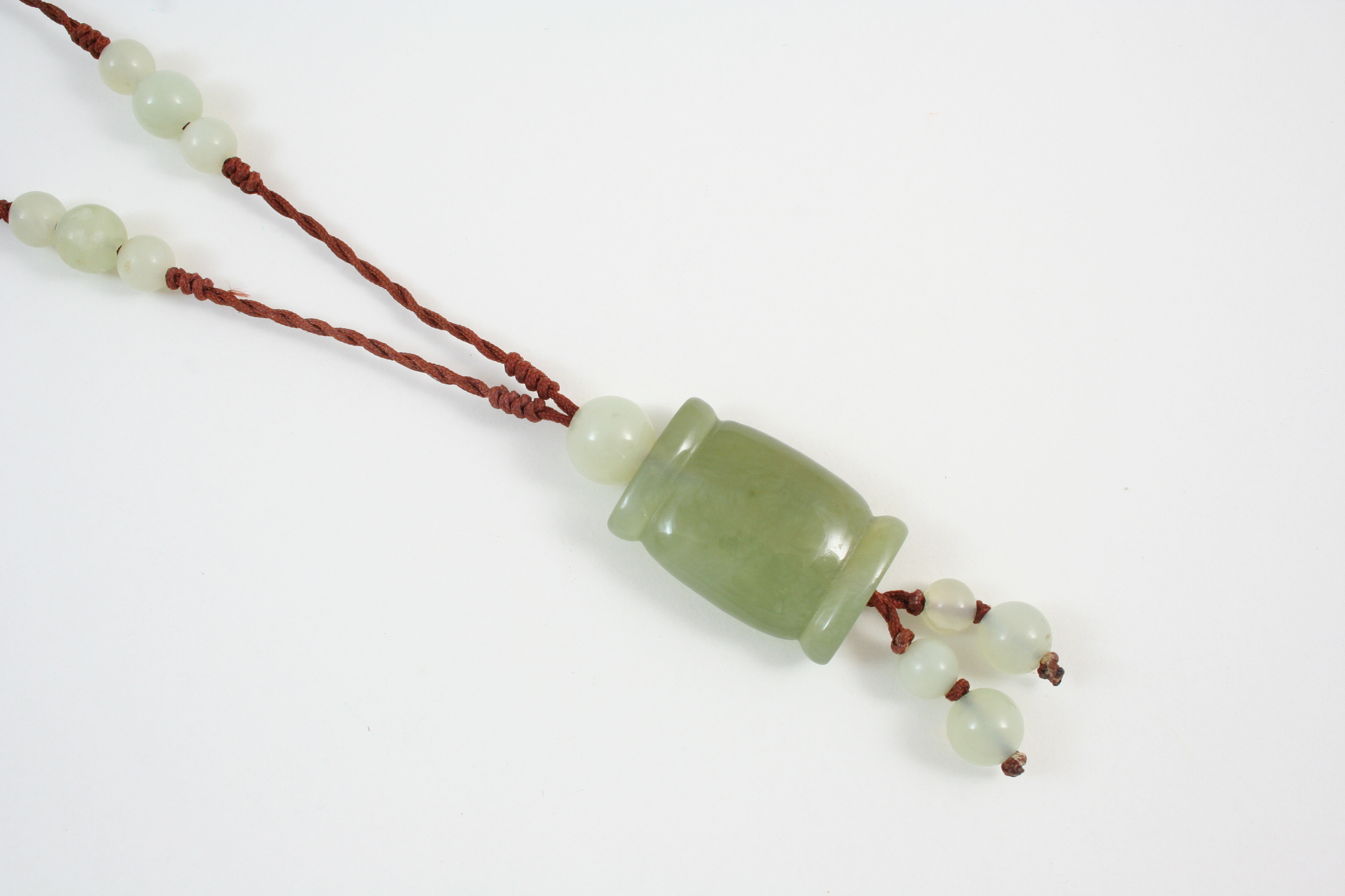 A CHINESE JADE PENDANT formed with a rounded rectangular-shaped section of jade, on silk mounted
